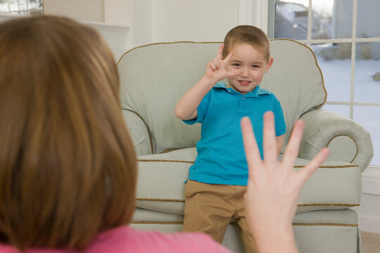 Woman signing the number '4' in American sign language while communicating with her son