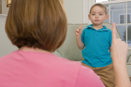 Woman signing the number '1' in American sign language while communicating with her son
