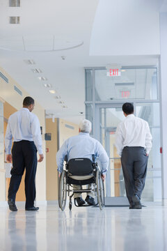 Rear view of three professors in a corridor, one with Muscular Dystrophy