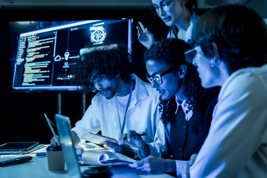 Female developer present financial report on screen. Diverse software engineer team discuss business growth chart, computer program code, and tech startup strategy in office meeting