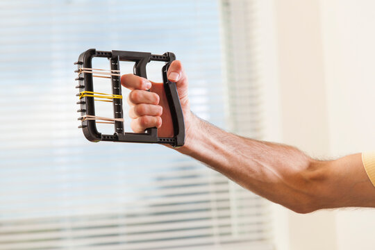 Man with Friedreich's Ataxia with deformed hands using hand strengthening equipment