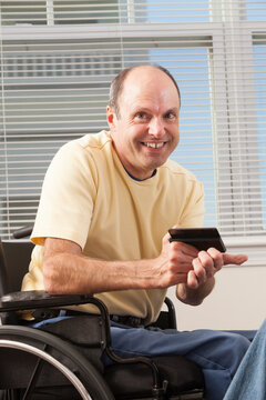 Man with Friedreich's Ataxia in wheelchair reading a smart phone
