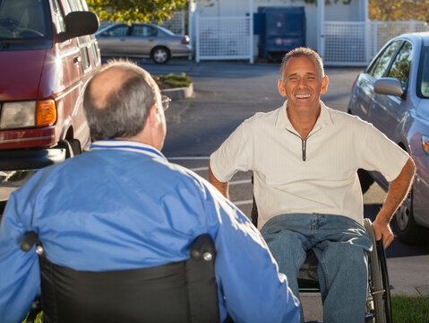 Man with Friedreich's Ataxia greeting his friend with spinal cord injury