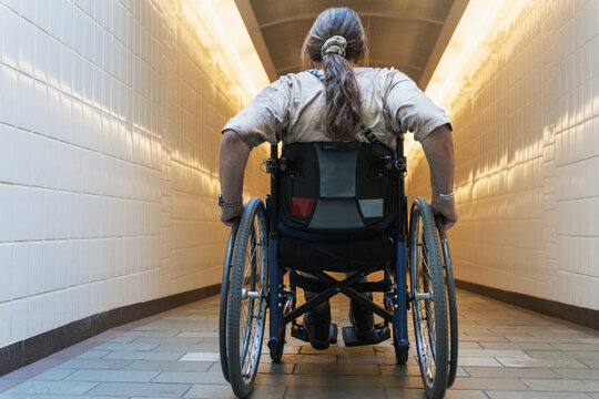 Woman with spinal cord injury in a wheelchair accessing subway train station