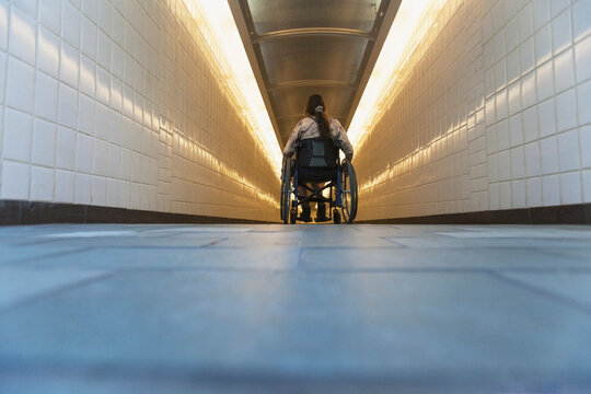 Woman with spinal cord injury in a wheelchair accessing subway train station