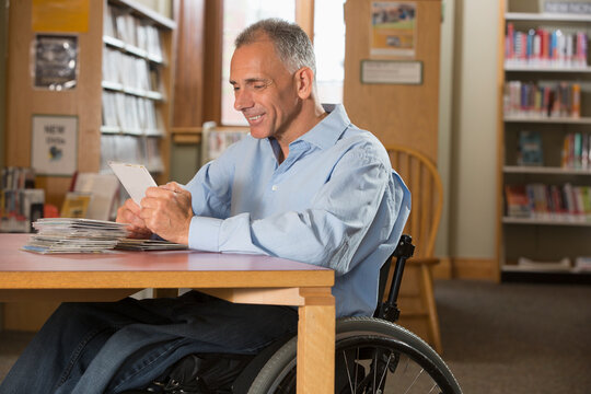 Man in a wheelchair with a Spinal Cord Injury in a library looking at DVDs