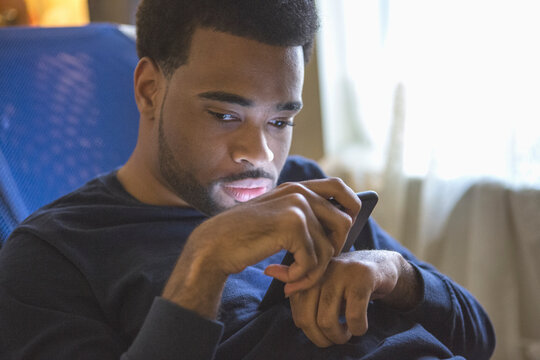 African American man with Cerebral Palsy using his cell phone at home