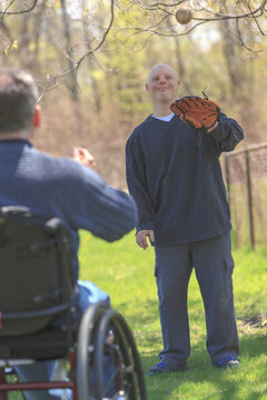 Father with Spinal Cord Injury and his son with Down Syndrome playing baseball in a park