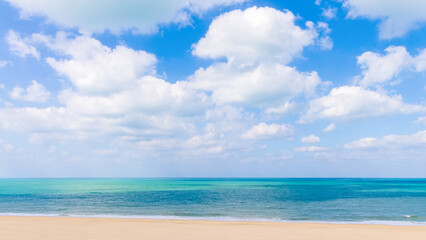 Fototapeta premium Beautiful tropical beach background with golden sand, turquoise sea water and white clouds on blue sky. Ajman, UAE