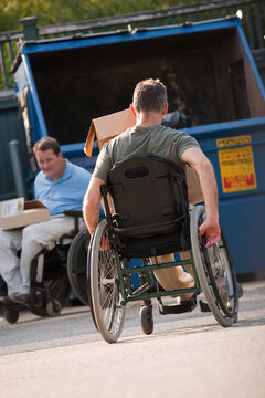 Men in wheelchairs with Spinal Cord Injuries moving trash to the dumpster
