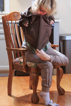 Woman with TAR Syndrome putting on her jacket and zipping it with her feet