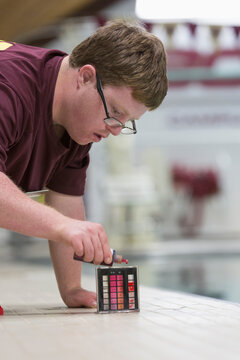 Young man with Down Syndrome working at college testing PH in swimming pool