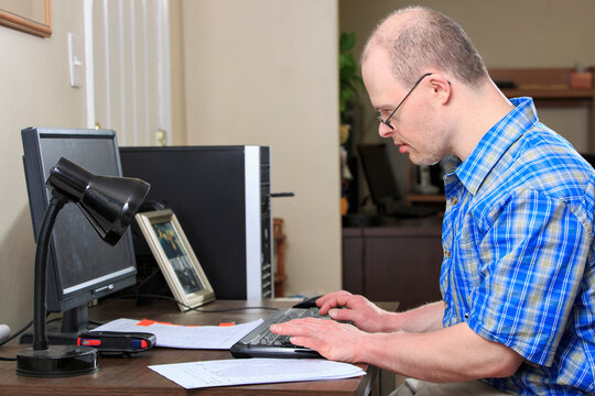 Man with Down Syndrome working at his computer in an office