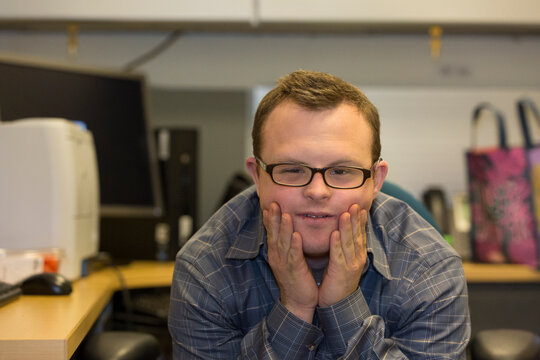 Portrait of hospital aid worker with Down Syndrome sitting at his desk