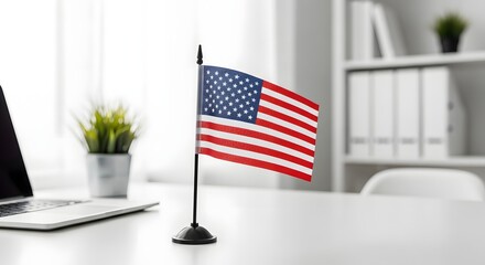 Fototapeta premium Small American Flag on Office Desk with Laptop and Blurred Office Background USA Patriotic Concept