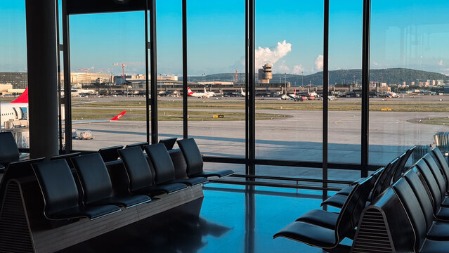 Zurich, Switzerland - May 29, 2025: View of Zurich Airport terminal with aircraft and mountains on a clear day
