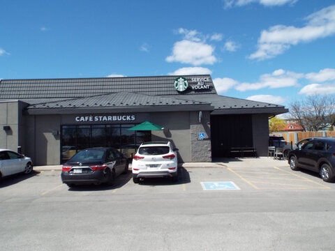 Gatineau, Quebec, Canada &ndash; May 9, 2026: "Cafe Starbucks" coffee shop storefront with "Service au volant" signage is shown with several cars parked in front today at 325 Bd Gr&eacute;ber.
