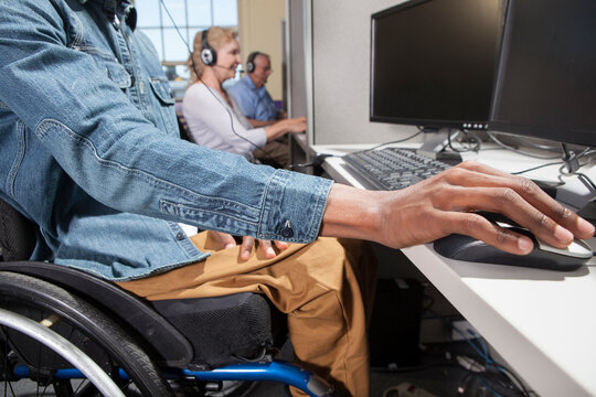 Man who had Spinal Meningitis in a wheelchair working at a booth in a call center