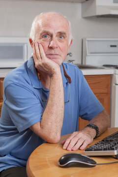 Portrait of a man with Ataxia relaxing at his computer in the kitchen