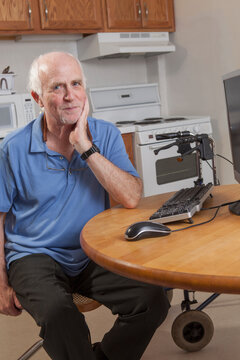 Portrait of a man with Ataxia relaxing at his computer in the kitchen