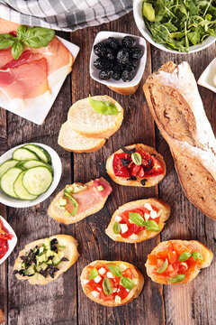 flat lay of italian antipasti ingredients and bruschetta on wood