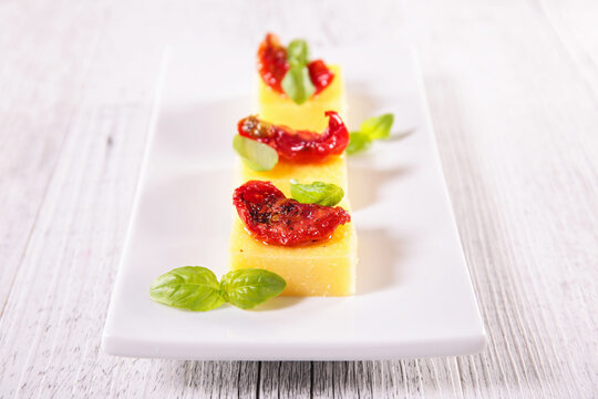 polenta cubes with sun dried tomatoes and basil appetizers on plate
