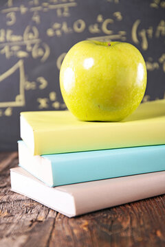 green apple on stack of books with math blackboard background