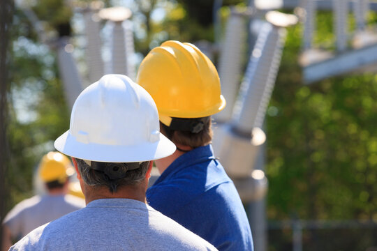 Power engineers looking at high voltage power distribution station