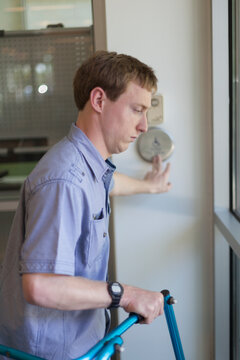 Young man with Cerebral Palsy using his walker while opening a door with a push button