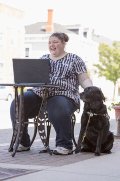 Woman with Visual Impairment sitting at a cafa&Atilde;&permil;a with her computer and service dog