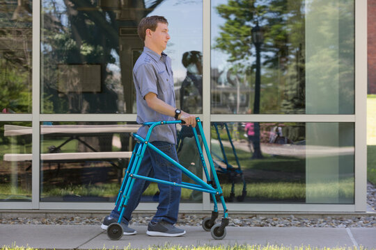 Young man with Cerebral Palsy using his walker to walk to work