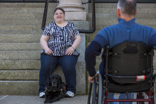 Man with Spinal Cord Injury sitting in wheelchair with his daughter in background who is Blind