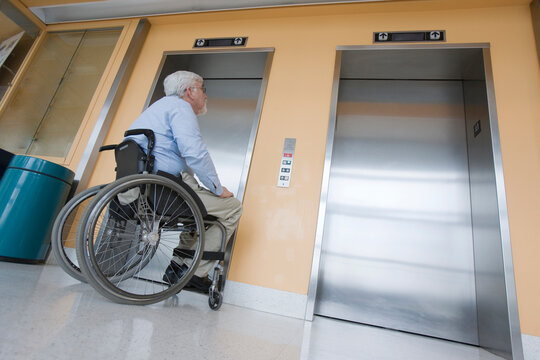 University professor with Muscular Dystrophy in a wheelchair waiting for an elevator