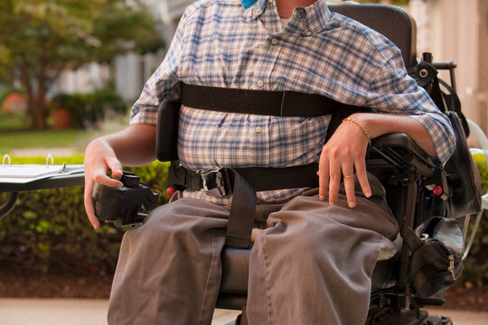 Man with Duchenne muscular dystrophy sitting in a motorized wheelchair using power controller with