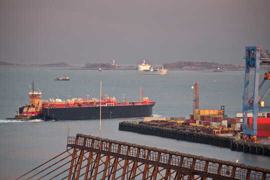 Container ship with cranes at a harbor with Nixes Mate and Boston Lighthouse in the background
