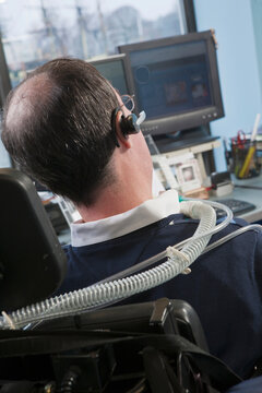 Businessman with Duchenne muscular dystrophy using a breathing ventilator in an office