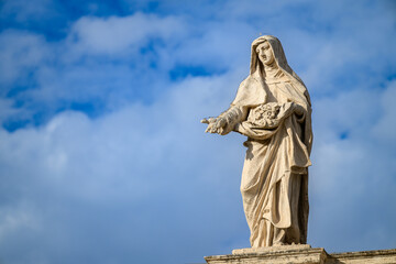 Obraz premium Saint Elizabeth of Portugal, sculpted by Lazzaro Morelli, atop the colonnade of St Peter’s Basilica in Vatican, Rome, Italy.