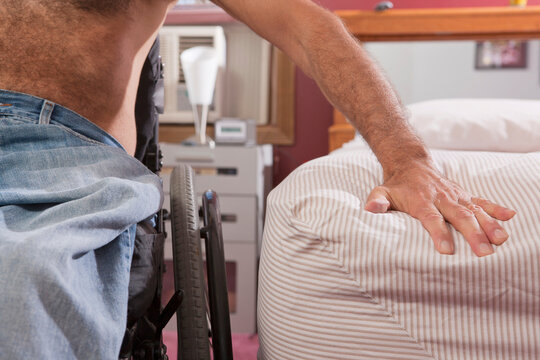 Man with spinal cord injury preparing to get into bed from his wheelchair