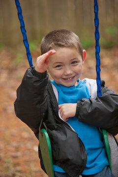 Boy signing the word 'Hello' in American Sign Language on a swing