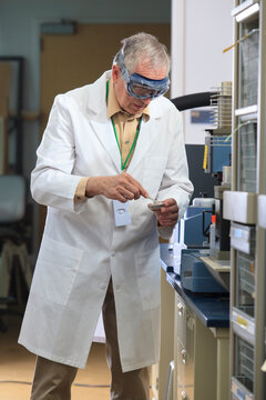 Professor wearing protective eyewear using tweezers to pick up reference sample for