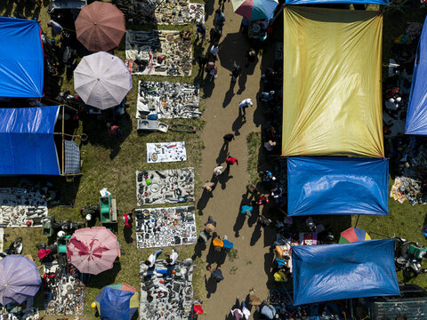 Aerial view of Bonyokan Pasar Legi with colorful market stalls, umbrellas, and people walking through the outdoor bazaar in Kecamatan Jatinom, Jawa Tengah, Indonesia.