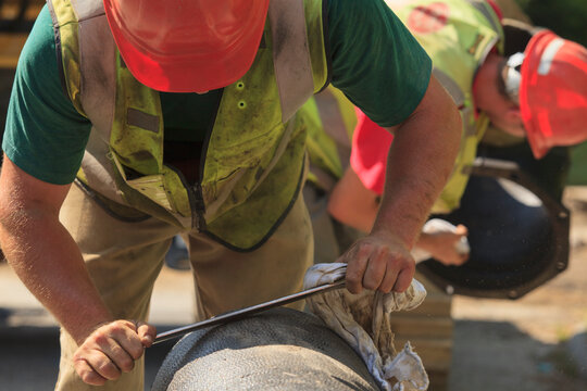 Construction worker smoothing rough edge of water main