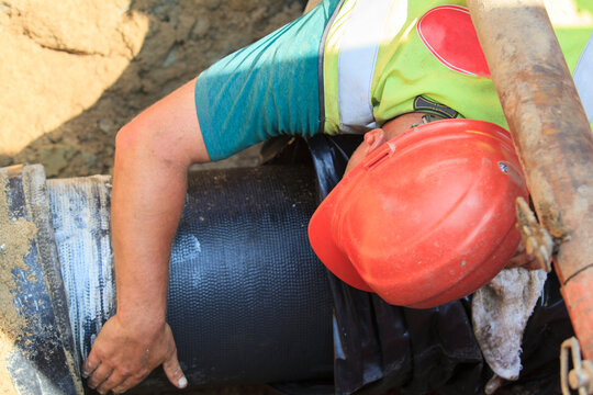Construction worker guiding water main into place