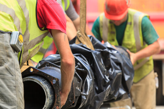 Construction workers guiding water main into place