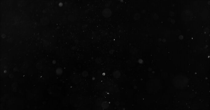 Realistic falling snow and airborne dust particles drifting through dark space. Atmospheric winter storm effect on black background, ideal for overlays, VFX compositing and cinematic scenes.