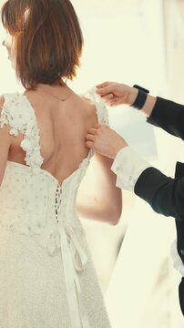 Wedding planner assisting bride with her gown
