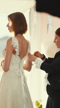 Bridesmaid helping bride with wedding dress preparation