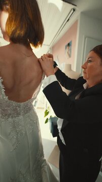 Fashion designer assisting bride with wedding dress fitting