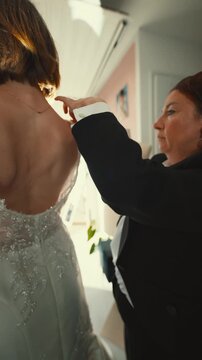 Fashion designer assisting a bride with her wedding gown fitting