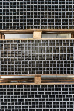 Planches en bois ins&eacute;r&eacute;es dans un quadrillage en m&eacute;tal, illustrant une structure moderne et industrielle aux mat&eacute;riaux contrast&eacute;s.